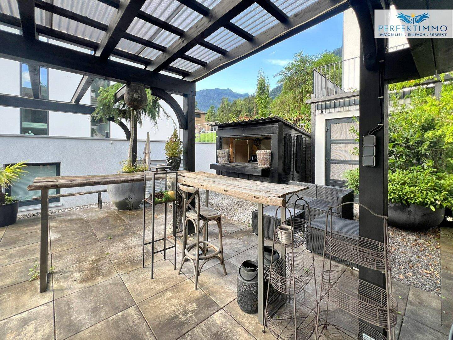 Große gepflasterte Terrasse mit Pergola und Outdoor-Sitzgelegenheiten.