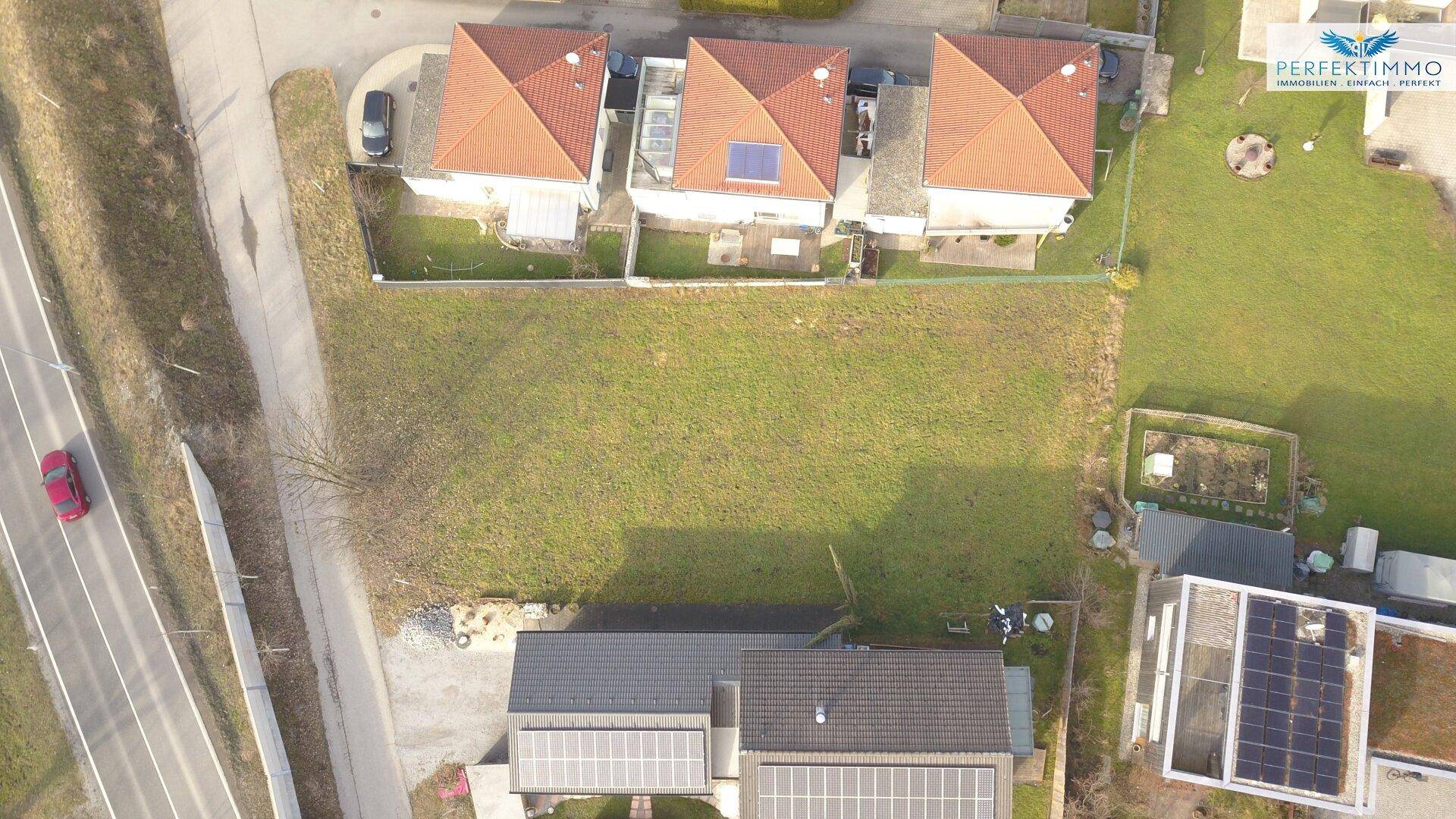 Luftaufnahme eines unbebauten Grundstücks in ländlicher Umgebung mit angrenzenden Häusern.