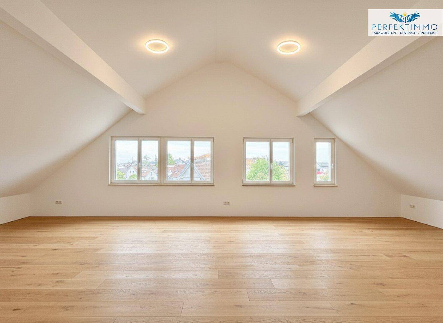 Großer, heller Raum im Dachgeschoss mit Holzboden, hohen Decken und mehreren Fenstern.
