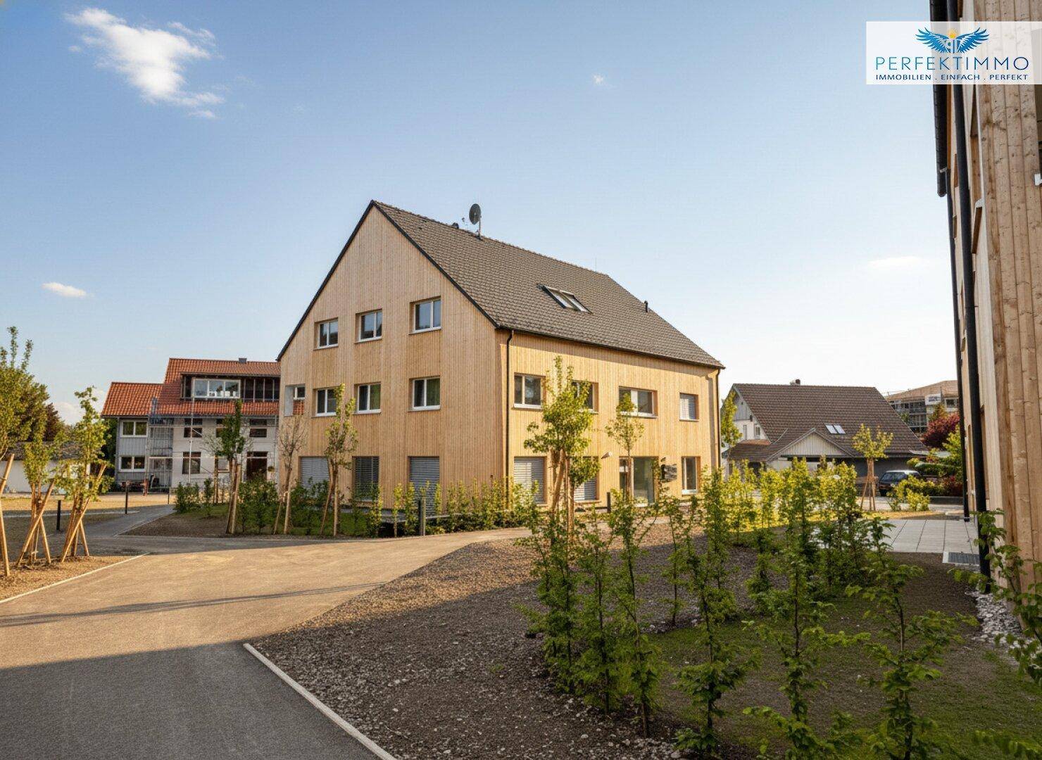 Neues Wohngebäude mit Holzfassade, Satteldach und gepflegter Außenanlage.