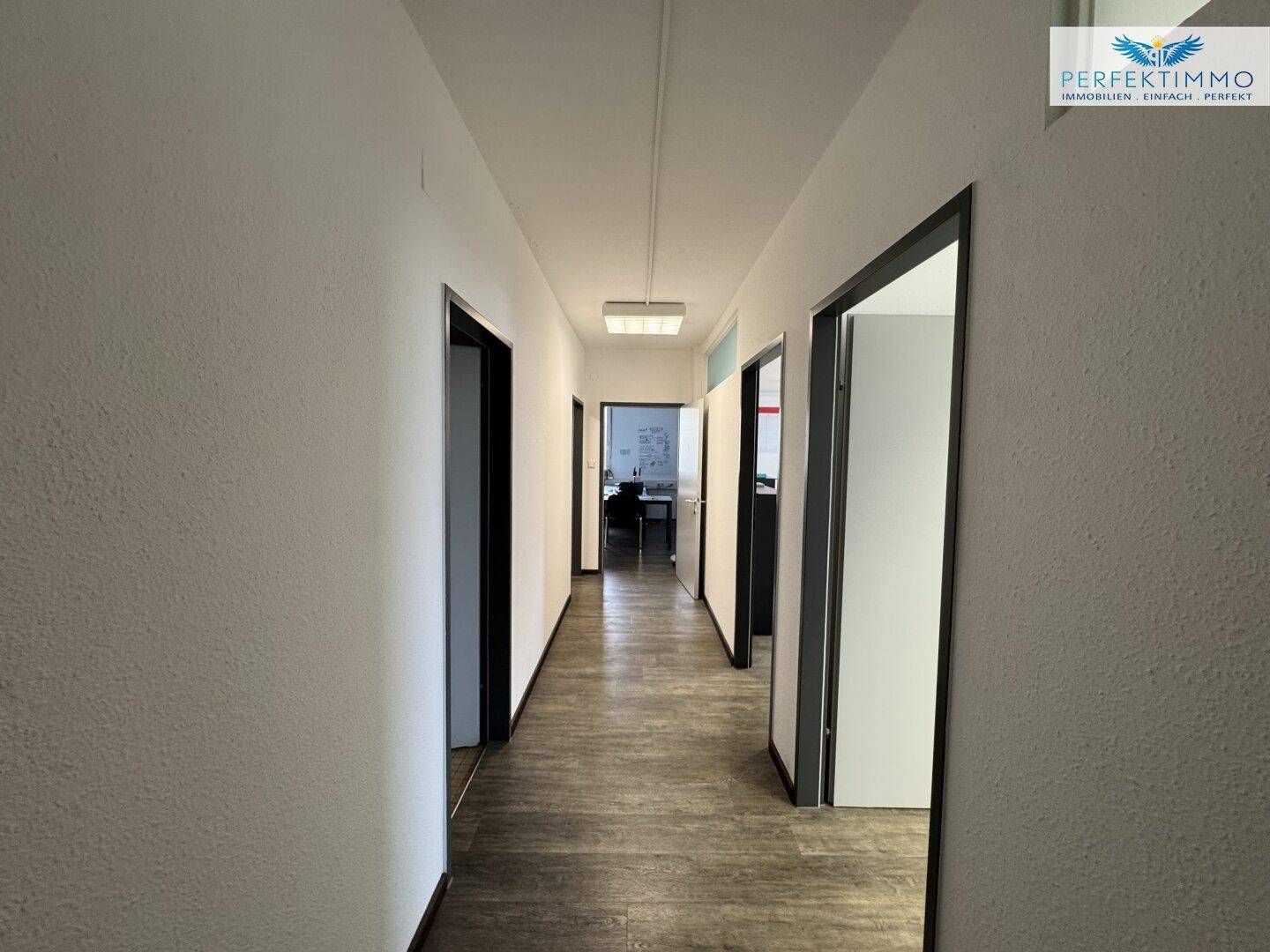 Langer, heller Flur mit mehreren Türen, der die verschiedenen Bürobereiche miteinander verbindet.