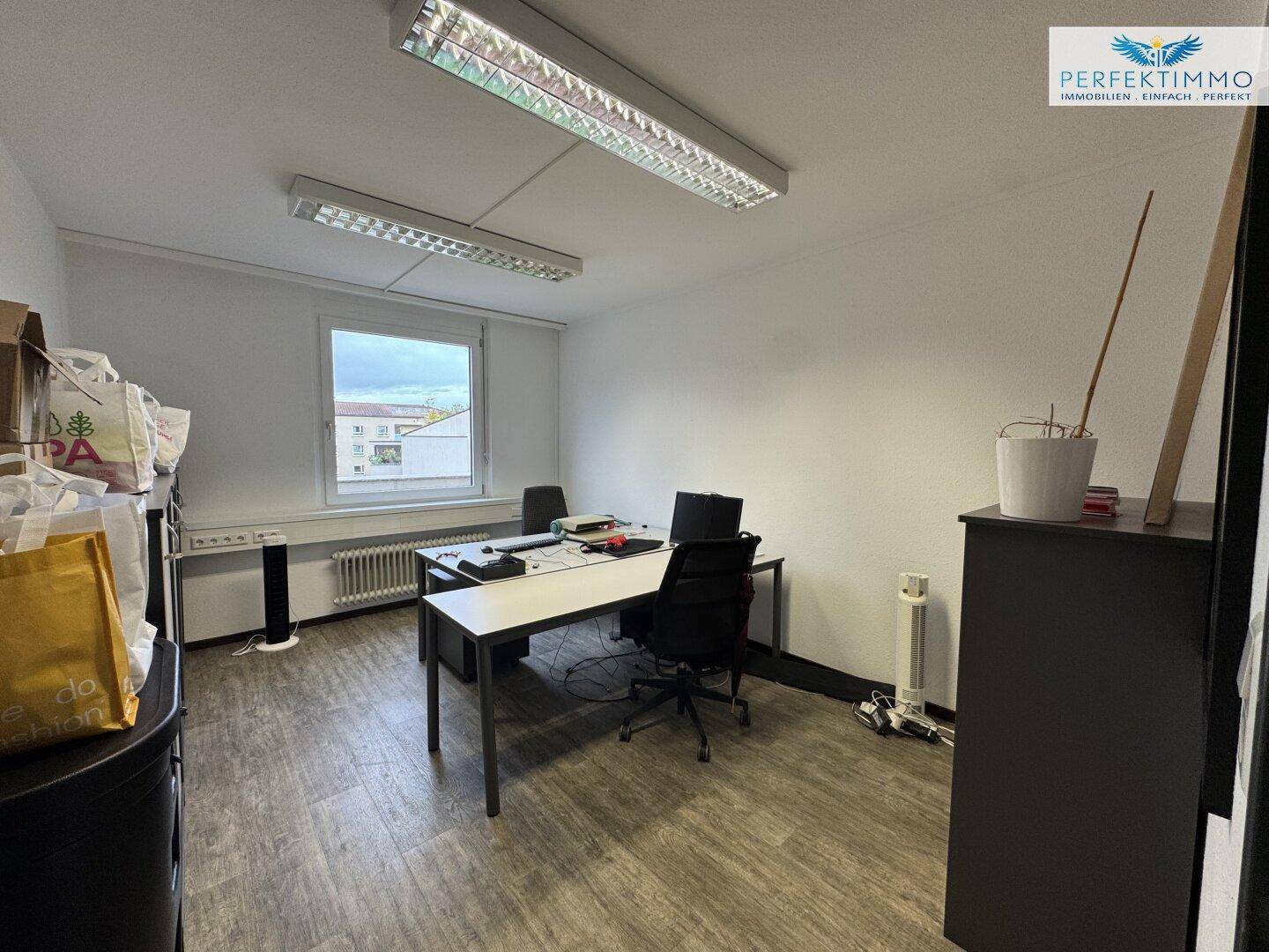 Einzelbüro mit Schreibtisch, Bürostuhl und Fenster, das für ausreichend Tageslicht sorgt.