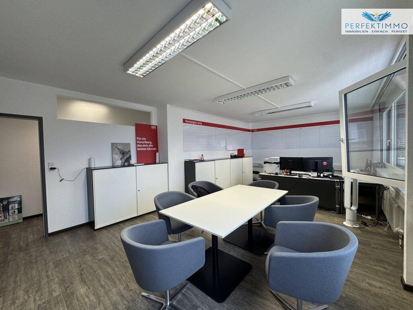 Modernes Büro mit Konferenztisch, bequemen Stühlen und großen Fenstern für eine helle Arbeitsatmosphäre.