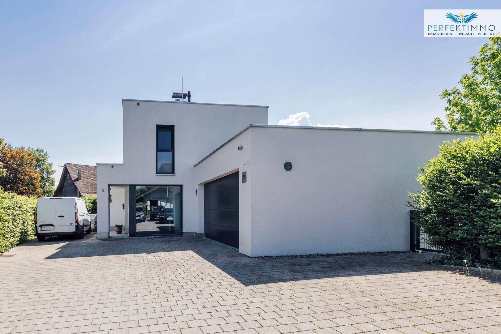 Vorderansicht des modernen Hauses mit Garage, gepflasterter Einfahrt und Haupteingang.