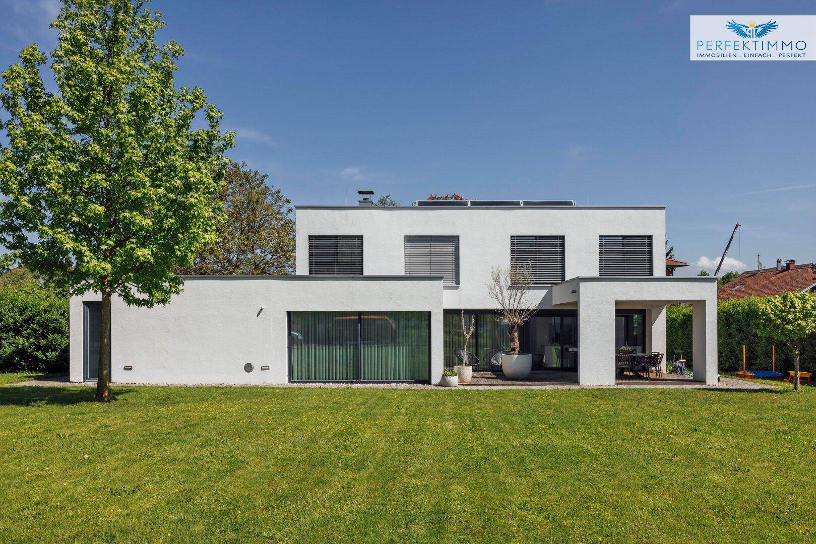 Ansicht des modernen Einfamilienhauses mit großen Fensterfronten und gepflegtem Rasen.