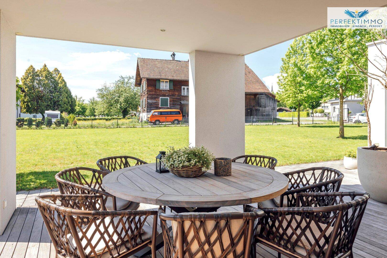 Gemütlicher Essbereich auf der überdachten Terrasse mit Blick auf die grüne Landschaft.