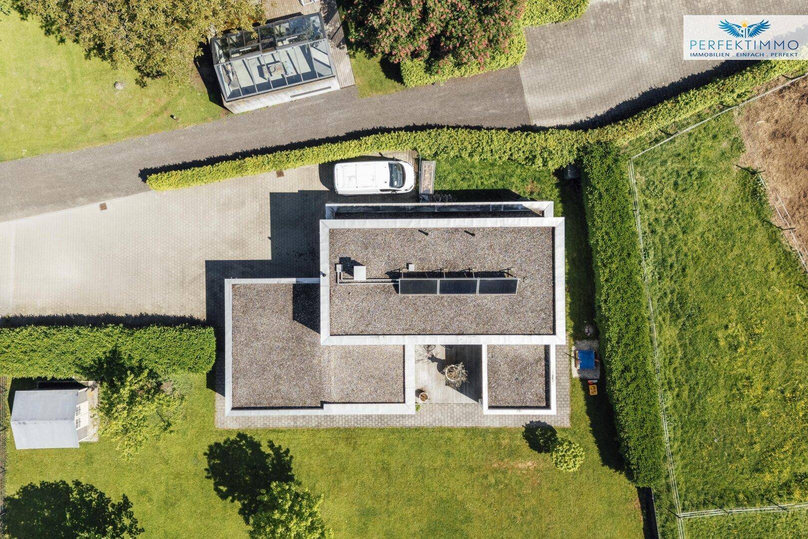 Vogelperspektive des Anwesens mit modernem Haus, Zufahrt, Garage und weitläufigen Grünflächen.