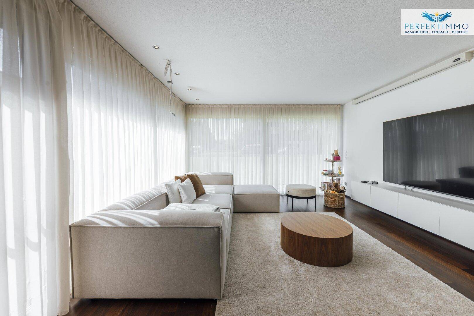 Helles Wohnzimmer mit beigem Sofa, Holztisch und dunklem Parkettboden, ideal zum Entspannen.