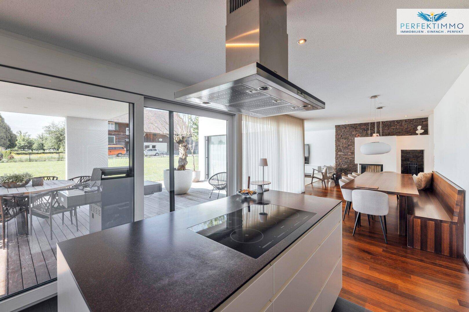 Offene Küche mit Blick auf den Essbereich und Zugang zur Terrasse durch große Glasschiebetüren.