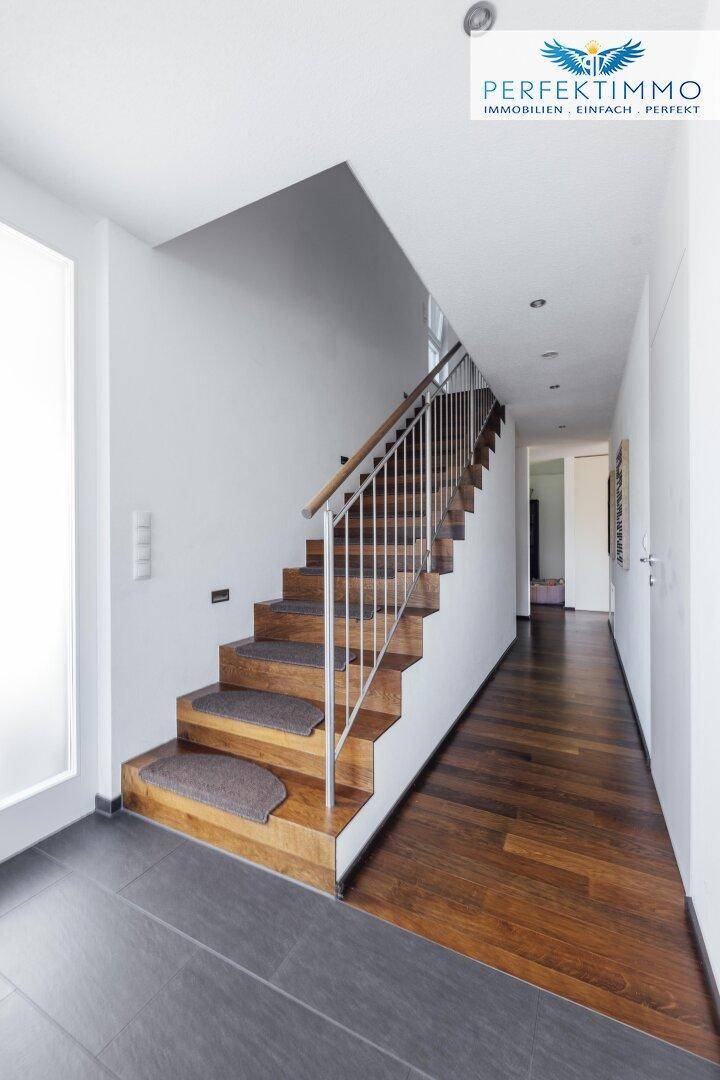 Heller Flur mit eleganter Holztreppe und einer Kombination aus Fliesen- und Parkettboden.