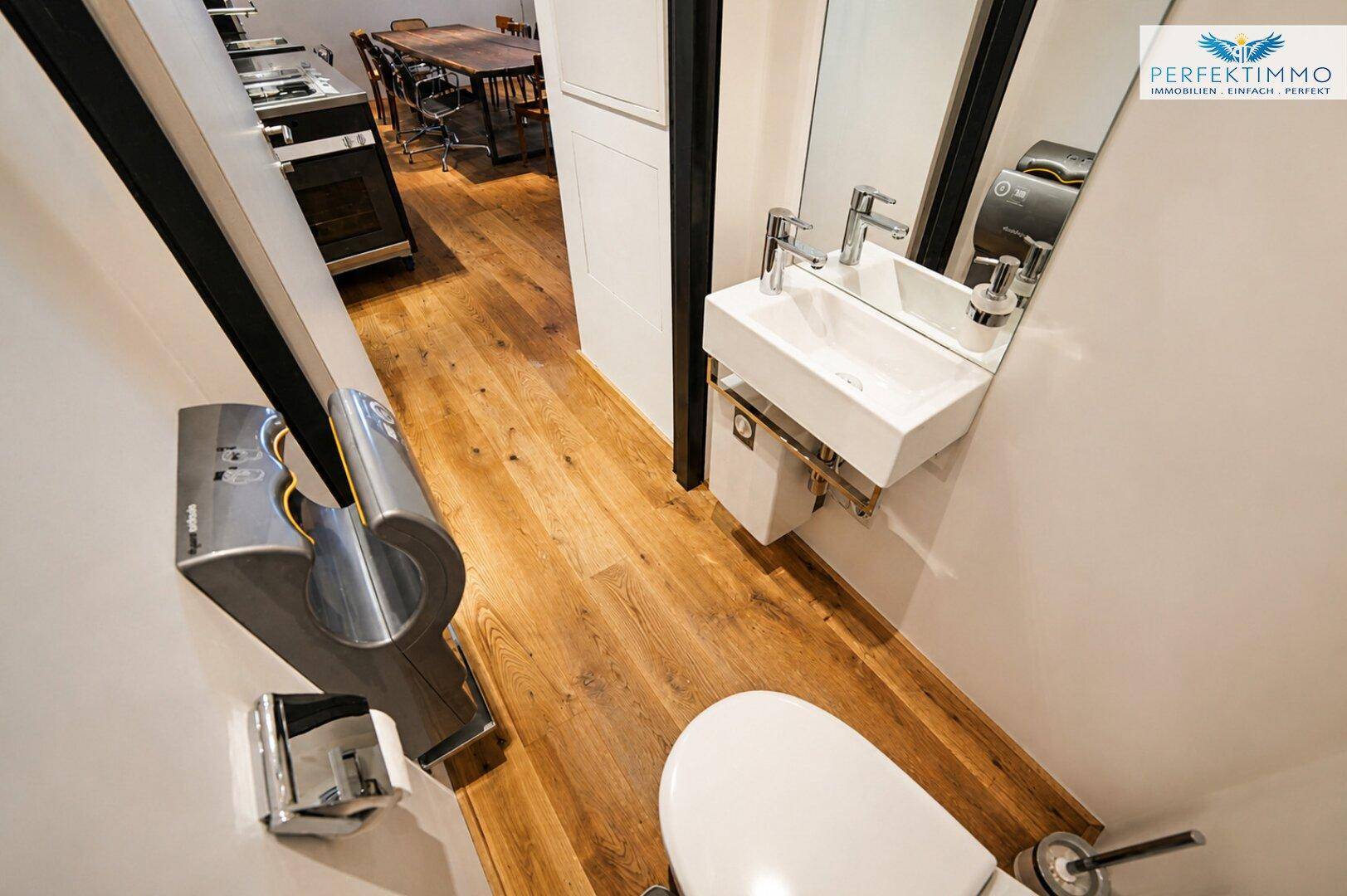 Modernes Gäste-WC mit kleinem Waschbecken, Wand-WC und Holzboden.