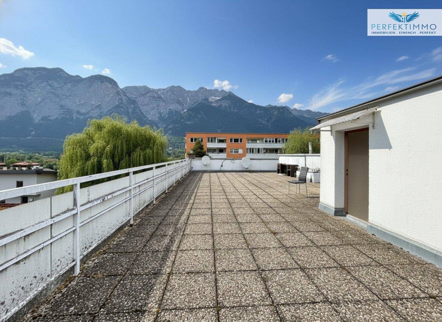 Weitläufige Dachterrasse mit Fliesenboden und atemberaubendem Panoramablick auf die umliegenden Berge.
