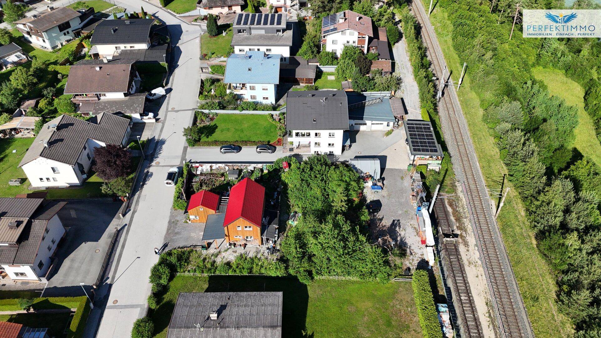 Panoramische Luftansicht eines ländlichen Wohngebiets mit Einfamilienhäusern und angrenzender Bahntrasse.
