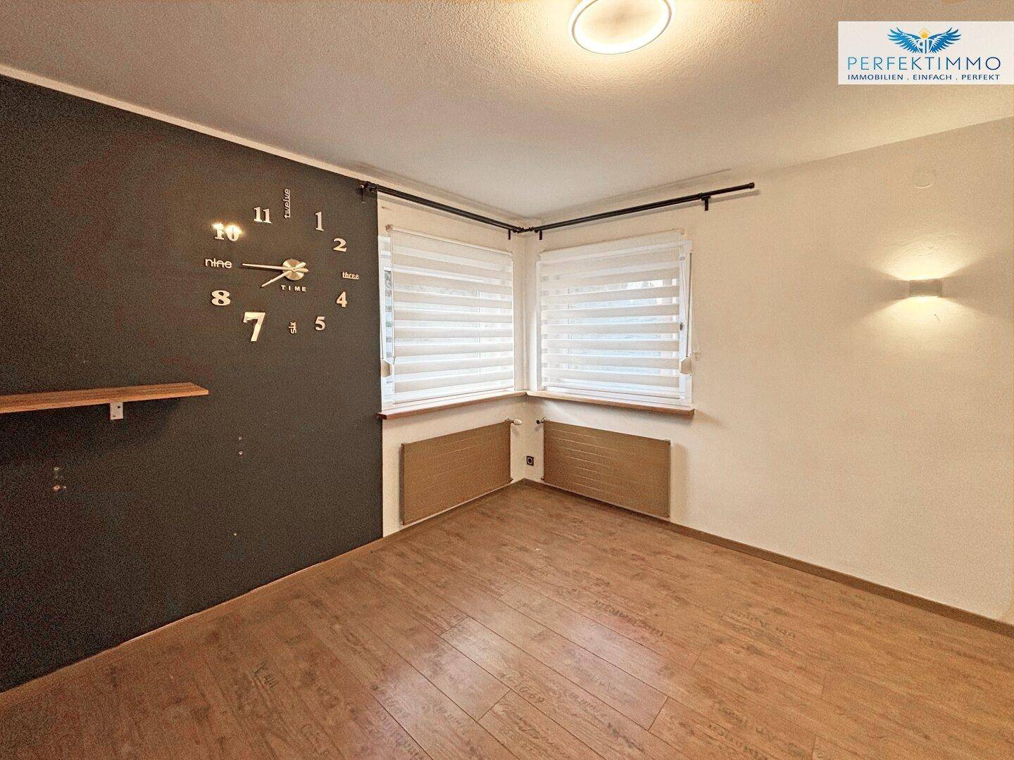 Helles Zimmer mit Holzboden und dekorativer Wandgestaltung, bereit zur individuellen Einrichtung.