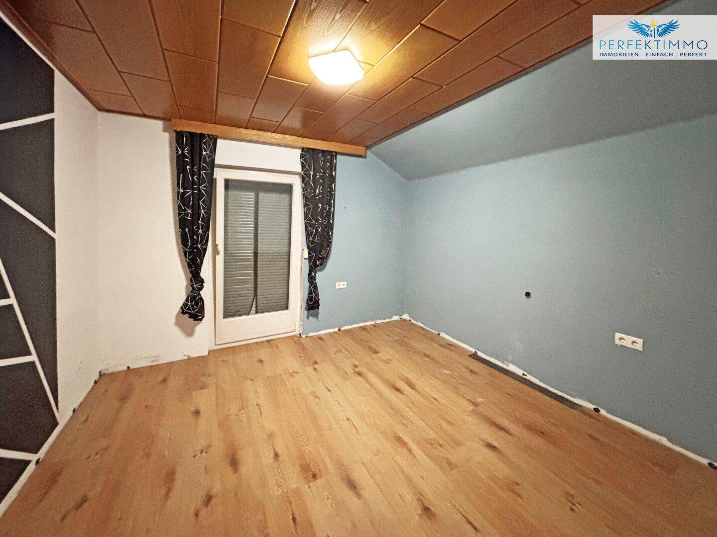 Geräumiges Zimmer mit Holzboden und Zugang zu einem Balkon, ideal für ein Schlafzimmer.