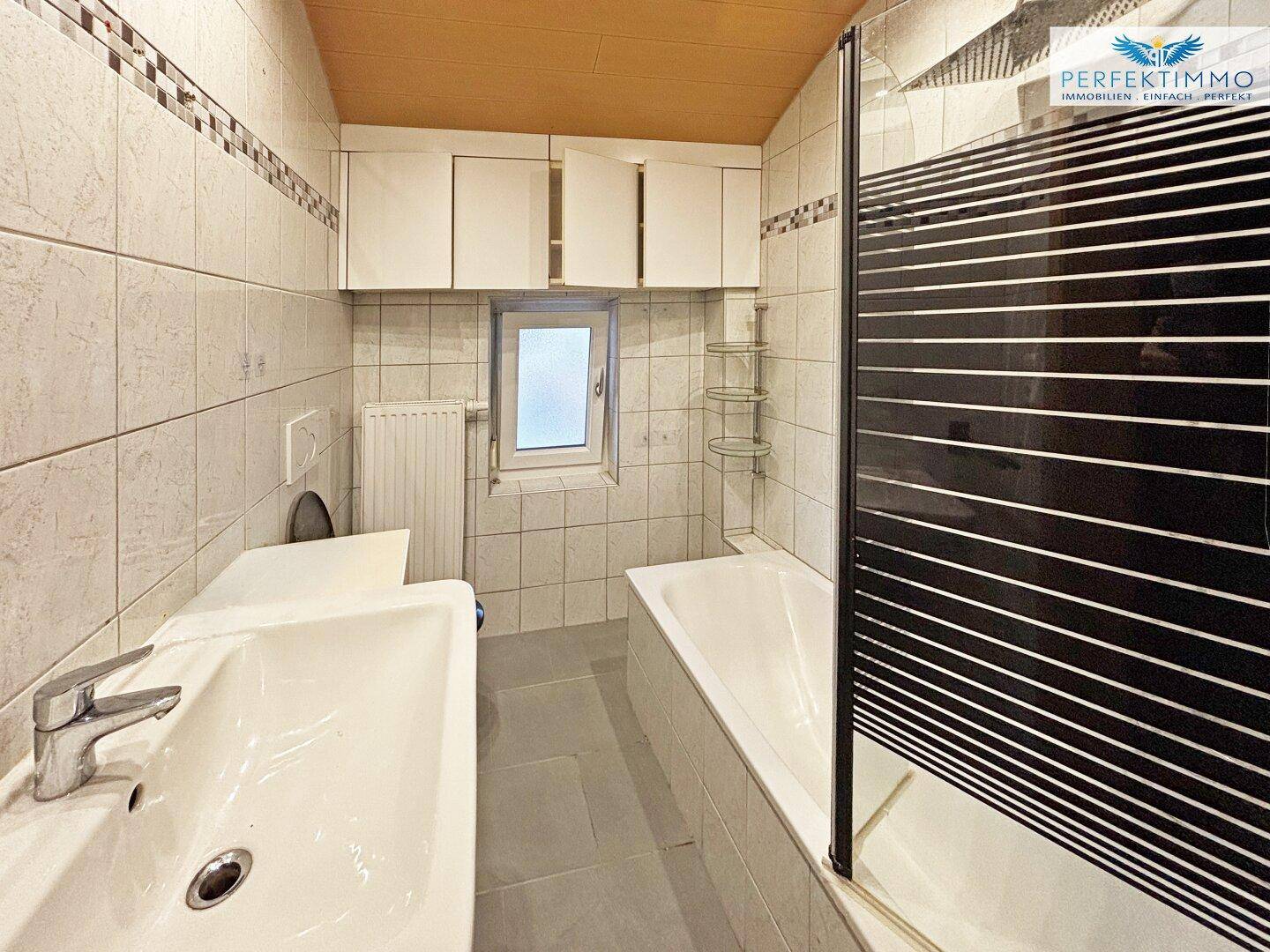 Funktionales Badezimmer mit Badewanne, Dusche und Fliesenboden in hellem Design.