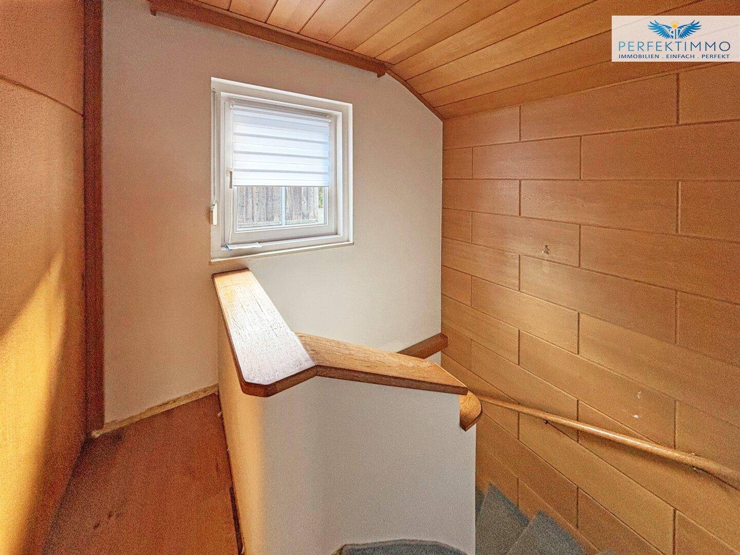 Treppenhaus mit Holzverkleidung und Geländer, das die verschiedenen Etagen verbindet.