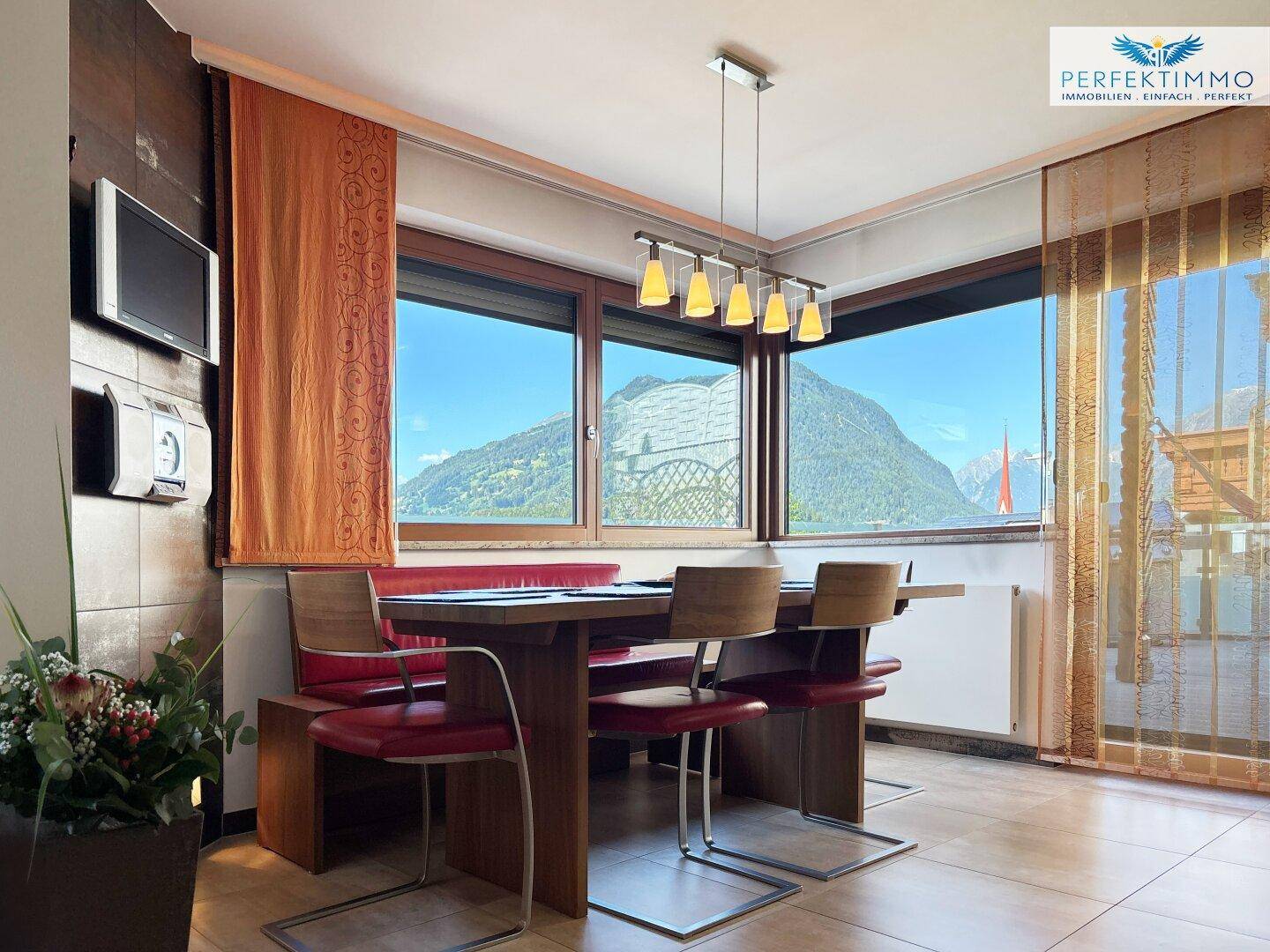 Gemütlicher Essbereich mit Eckbank und großen Fenstern, die einen weiten Bergblick bieten.