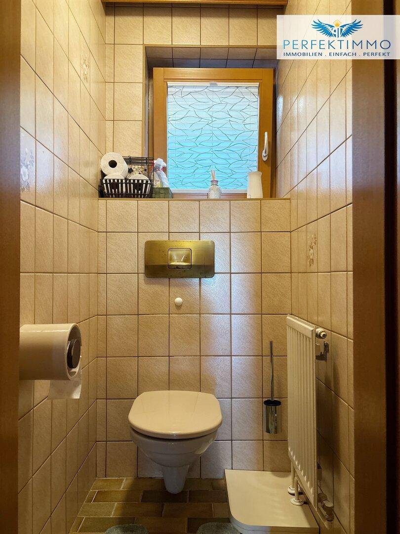 Kleines Gäste-WC mit Fliesenboden und Fenster für natürliche Belüftung.