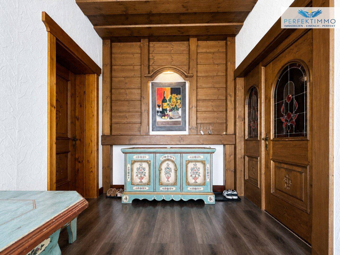 Traditioneller Eingangsbereich mit Holztäfelung, Holzboden und dekorativer Kommode im Landhausstil.