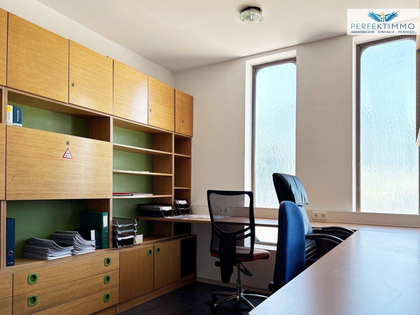 Helles Büro mit integrierten Holzregalen, Schreibtischen und hohen, schmalen Fenstern für viel Tageslicht.