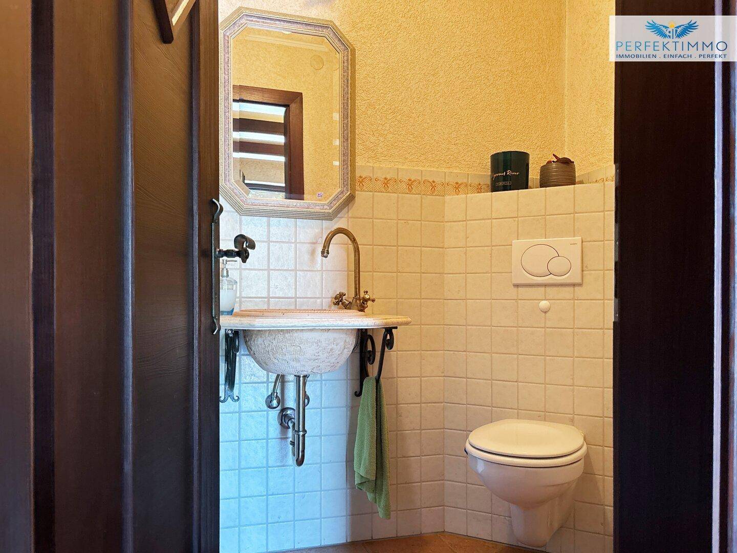 Gäste-WC mit kleinem Waschbecken, Toilette und hellen Fliesen, funktional und sauber.