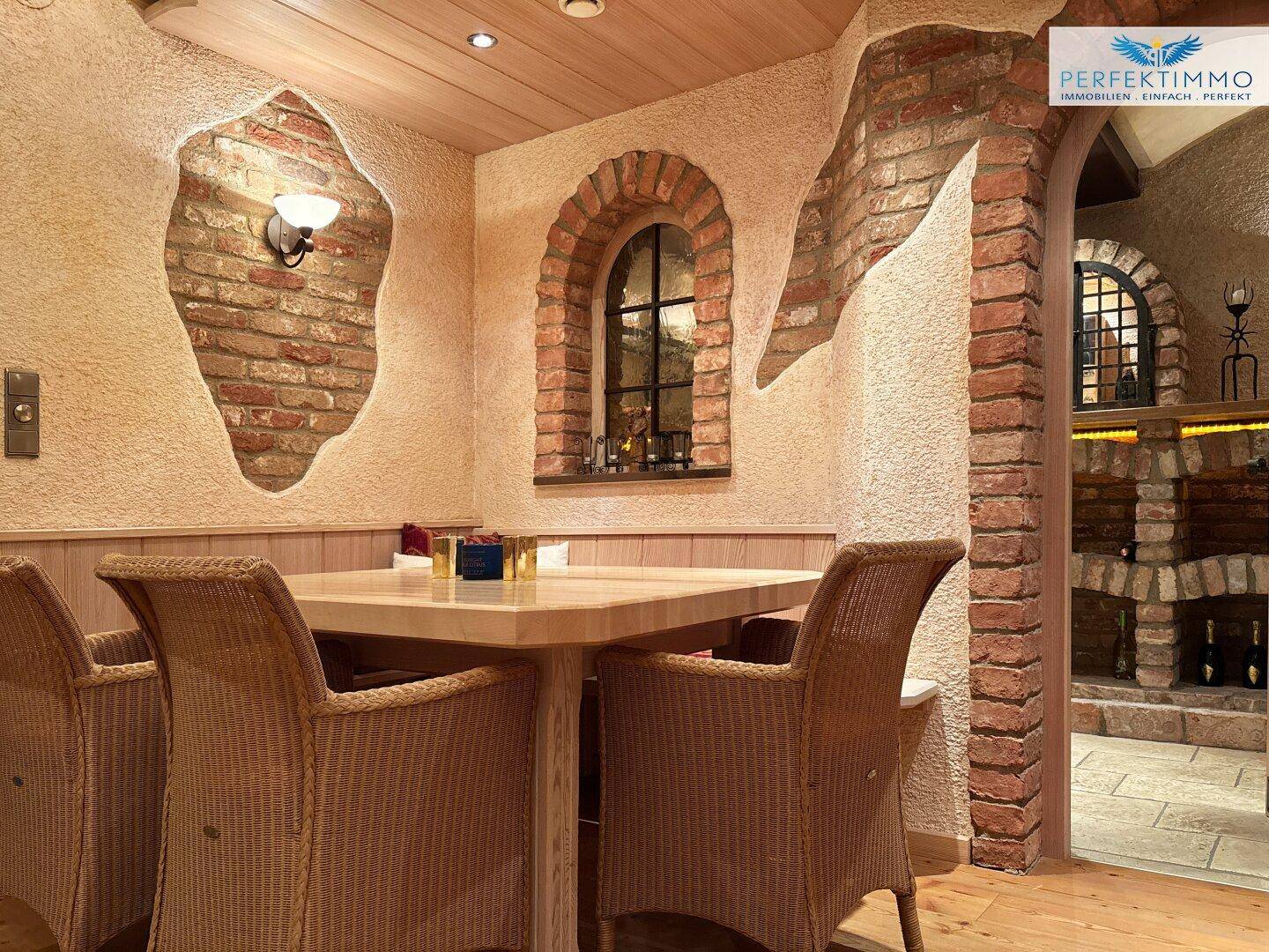 Gemütlicher Essbereich mit Korbstühlen, Holztisch und Ziegelwanddetails, perfekt für gesellige Runden.