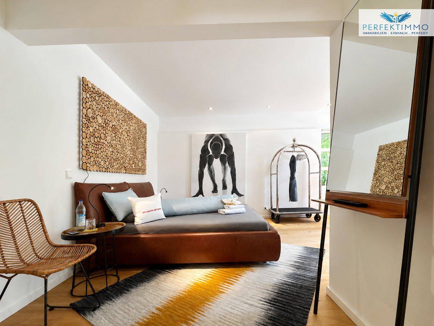 Modernes Schlafzimmer mit braunem Lederbett, Holzboden und dekorativer Wandkunst.