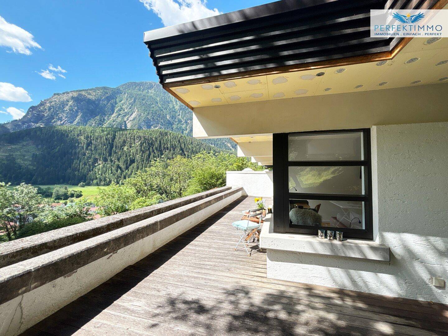 Große Holzterrasse mit Bergblick und Sitzgelegenheiten, ideal zum Entspannen im Freien.