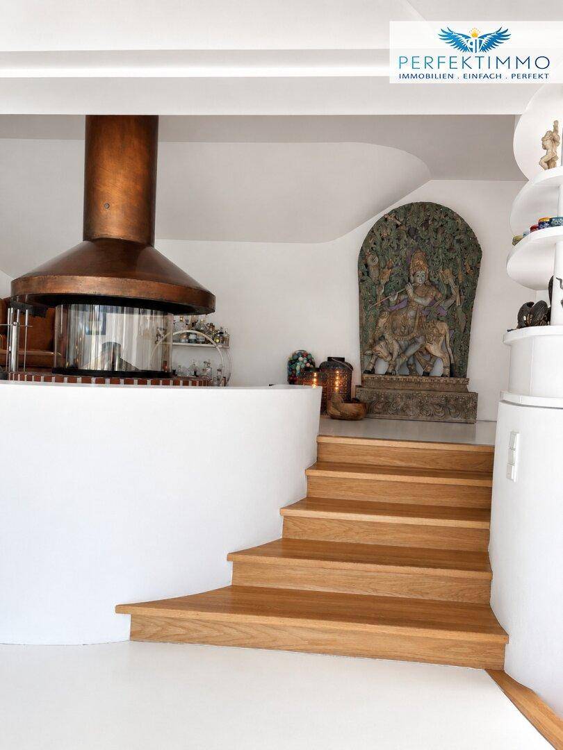 Holztreppe führt zu einem Bereich mit einer auffälligen Kupferhaube und Kunstwerken.