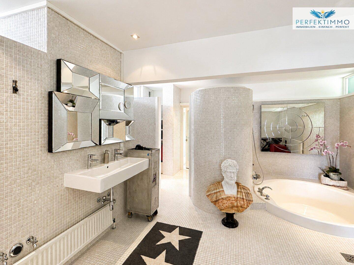 Geräumiges Badezimmer mit Mosaikfliesen, Badewanne und stilvollen Spiegelelementen.