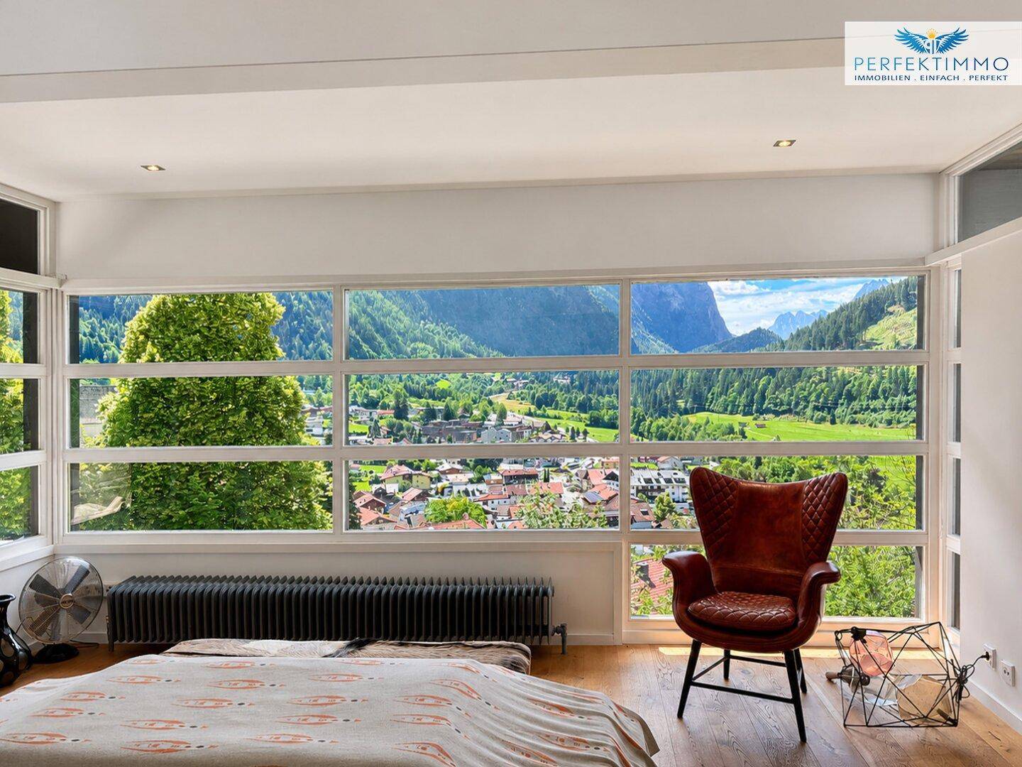 Schlafzimmer mit großen Fenstern, die einen weiten Blick auf die Berglandschaft bieten.