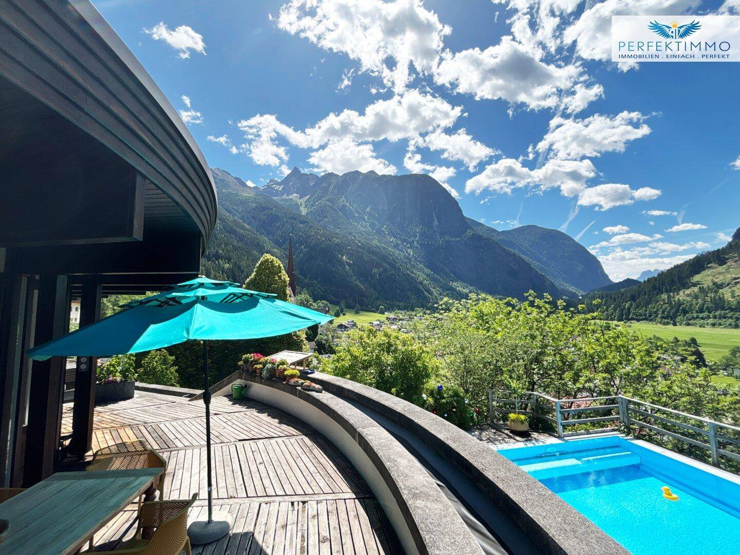 Große Holzterrasse mit Pool und atemberaubendem Panoramablick auf die umliegende Berglandschaft.