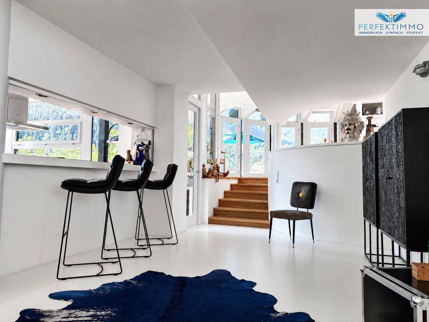 Offener Wohnbereich mit moderner Bar, Treppe und hellem Ambiente.