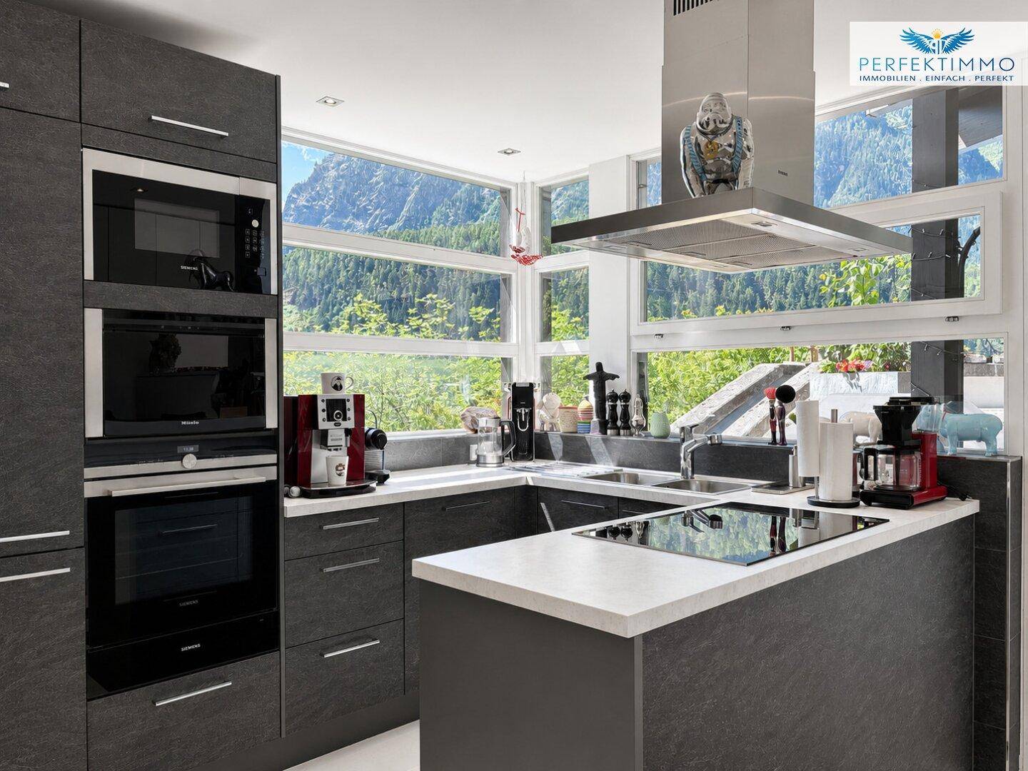 Hochmoderne Küche mit integrierten Geräten und weitem Blick auf die Berglandschaft.