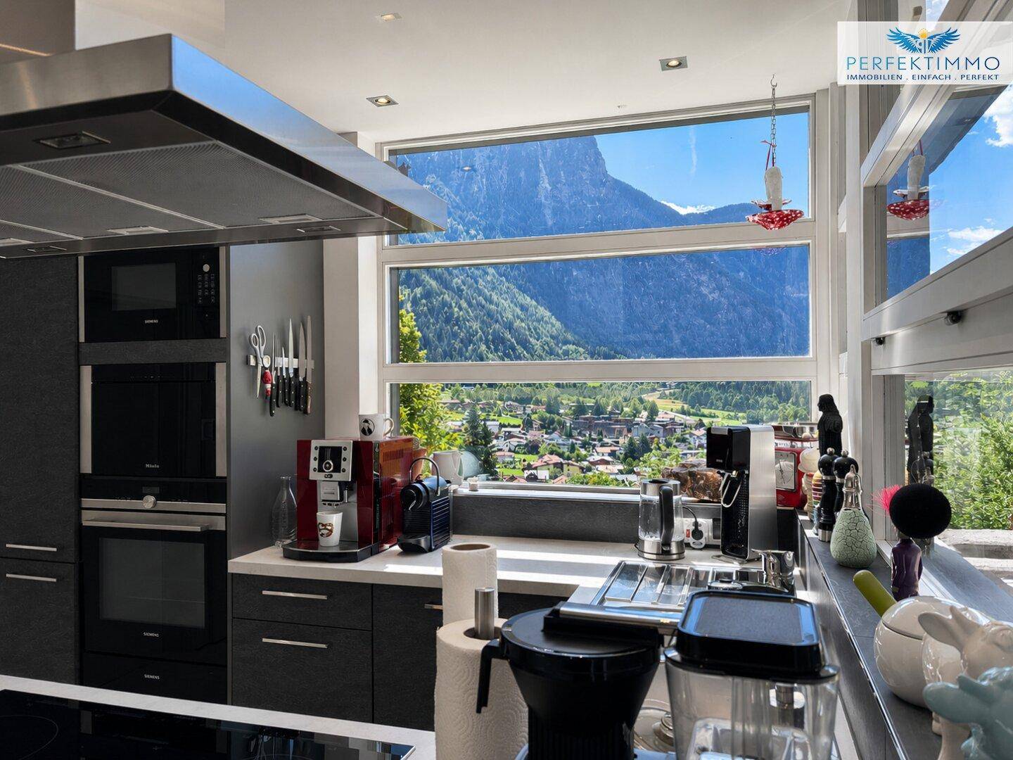 Stilvolle Küche mit hochwertigen Geräten und einem beeindruckenden Bergblick durch große Fenster.