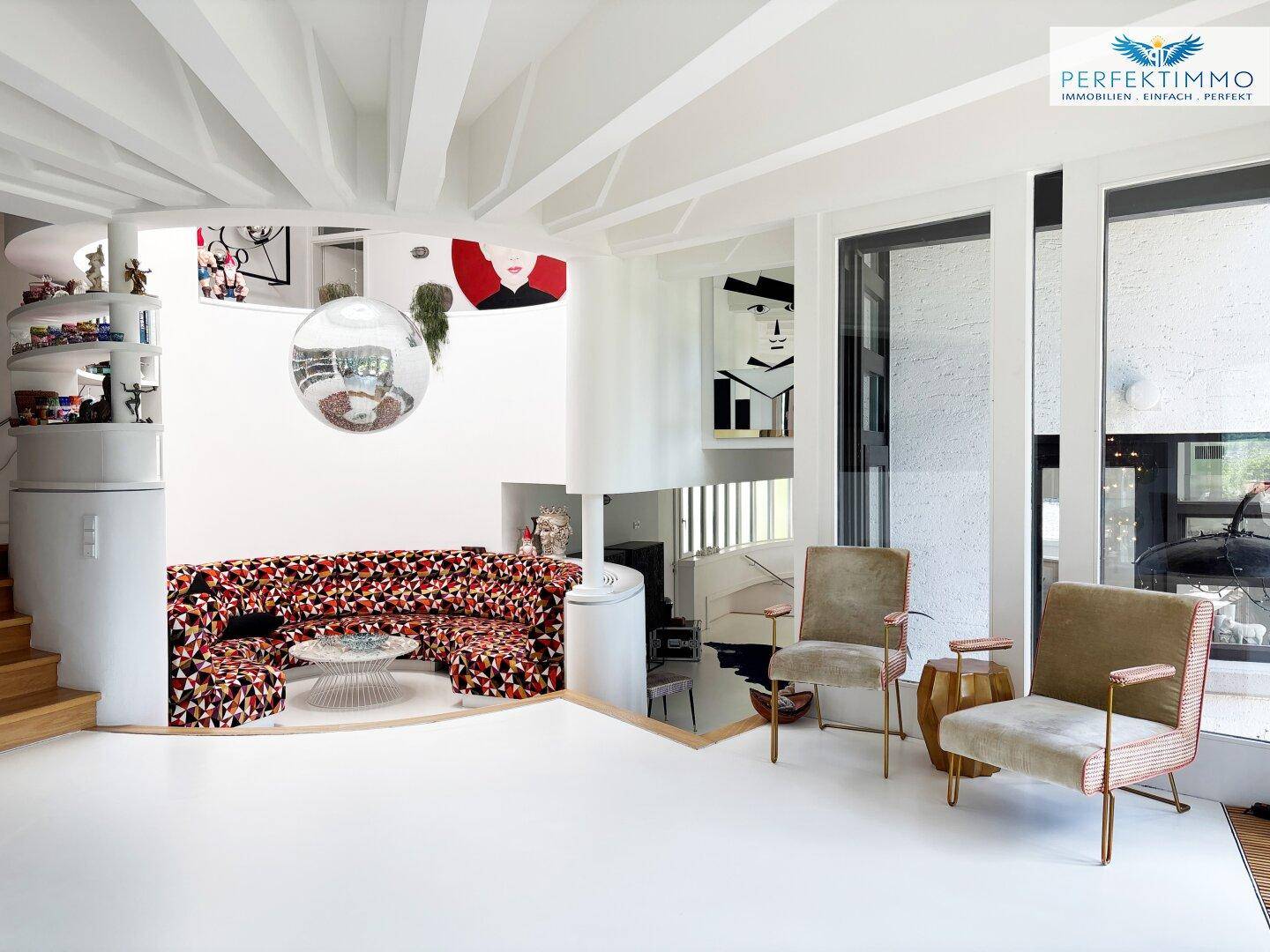 Geräumiges Wohnzimmer mit einzigartiger Sitzgelegenheit, Kunstwerken und viel Tageslicht.