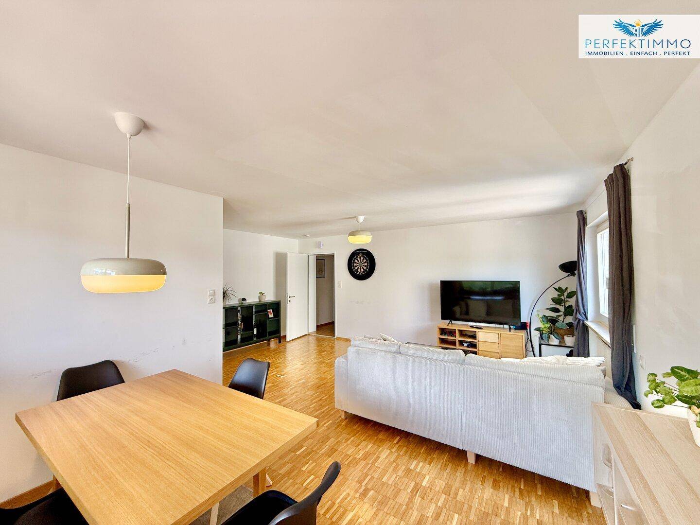 Gemütlicher Wohn- und Essbereich mit Holzboden, Sofa und einem Esstisch für gesellige Runden.