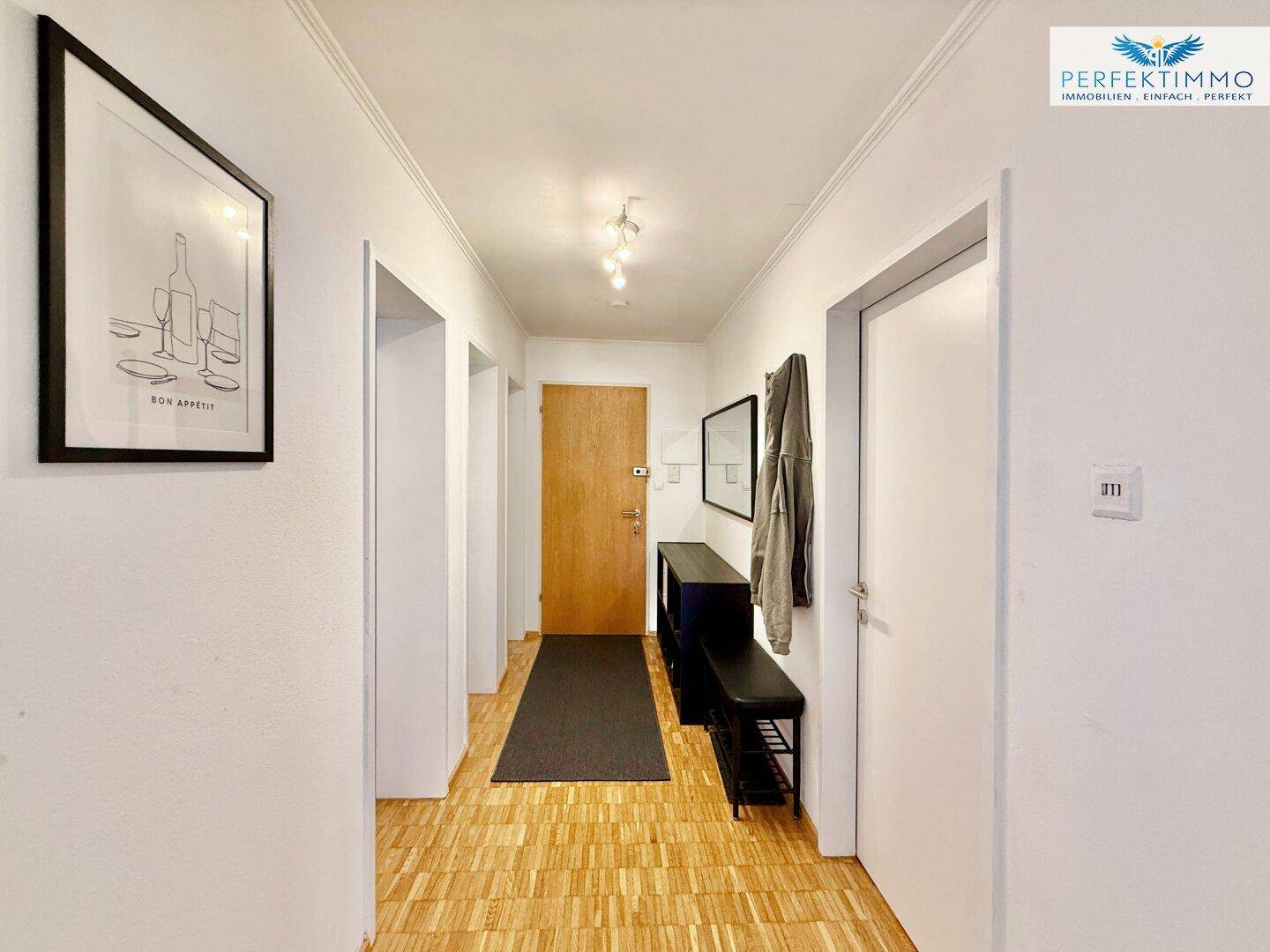 Heller Flur mit Parkettboden, Garderobe und einem Spiegel, der den Raum erweitert.