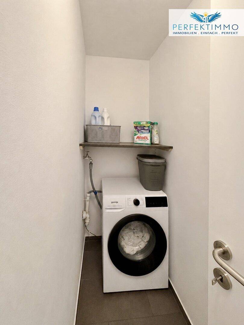Praktischer Hauswirtschaftsraum mit Waschmaschine und Regal für Reinigungsutensilien.
