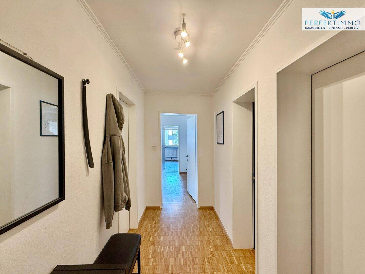Langer Flur mit Parkettboden und Zugang zu verschiedenen Zimmern der Wohnung.