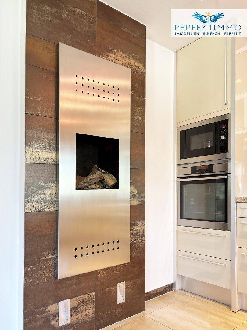 Integrierter Kamin in der Küche neben modernen Einbaugeräten und Mikrowelle.