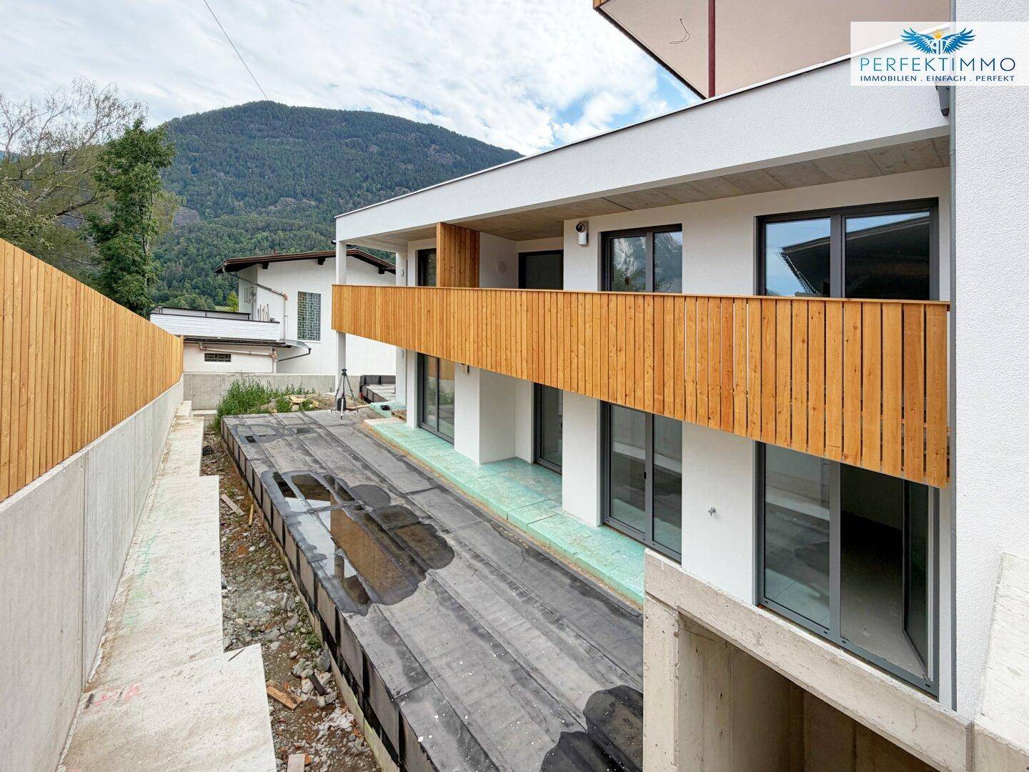 Balkonbereich im Bau mit Holzelementen und Blick auf die umliegende Berglandschaft.