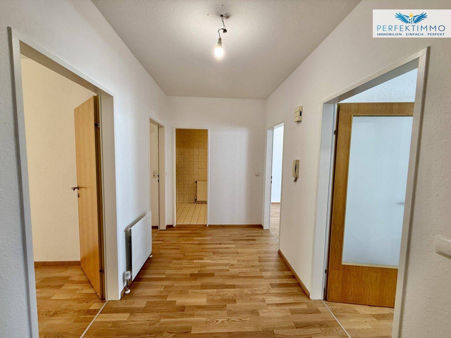 Heller Flur mit Parkettboden, der zu verschiedenen Zimmern der Wohnung führt.