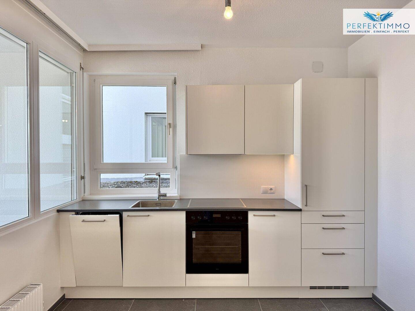 Gut ausgestattete Küchenzeile mit Backofen, Spülmaschine und Kühlschrank in Weiß.