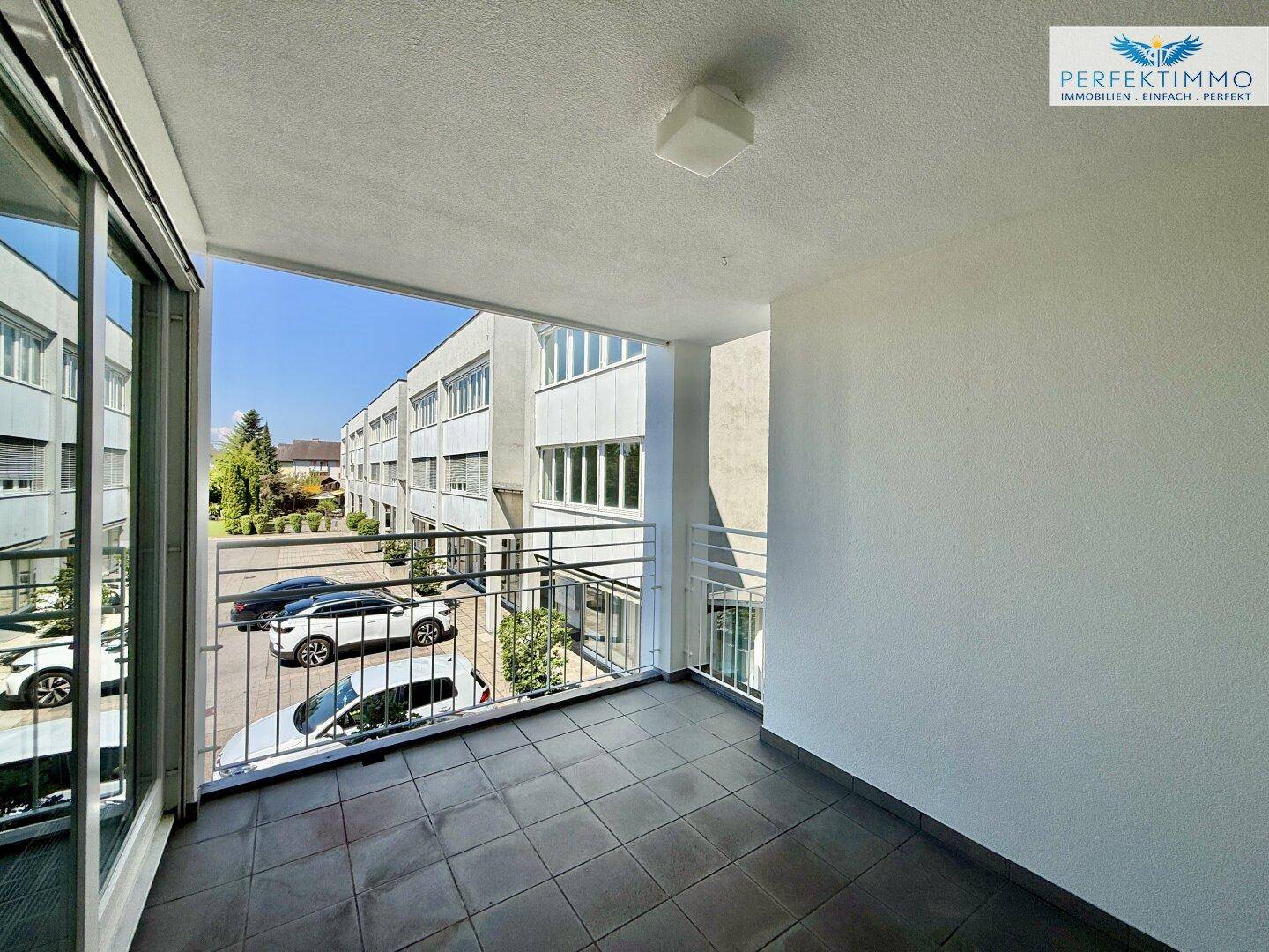 Heller Balkon mit Fliesen und Metallgeländer, bietet einen Ausblick auf die Nachbarschaft.