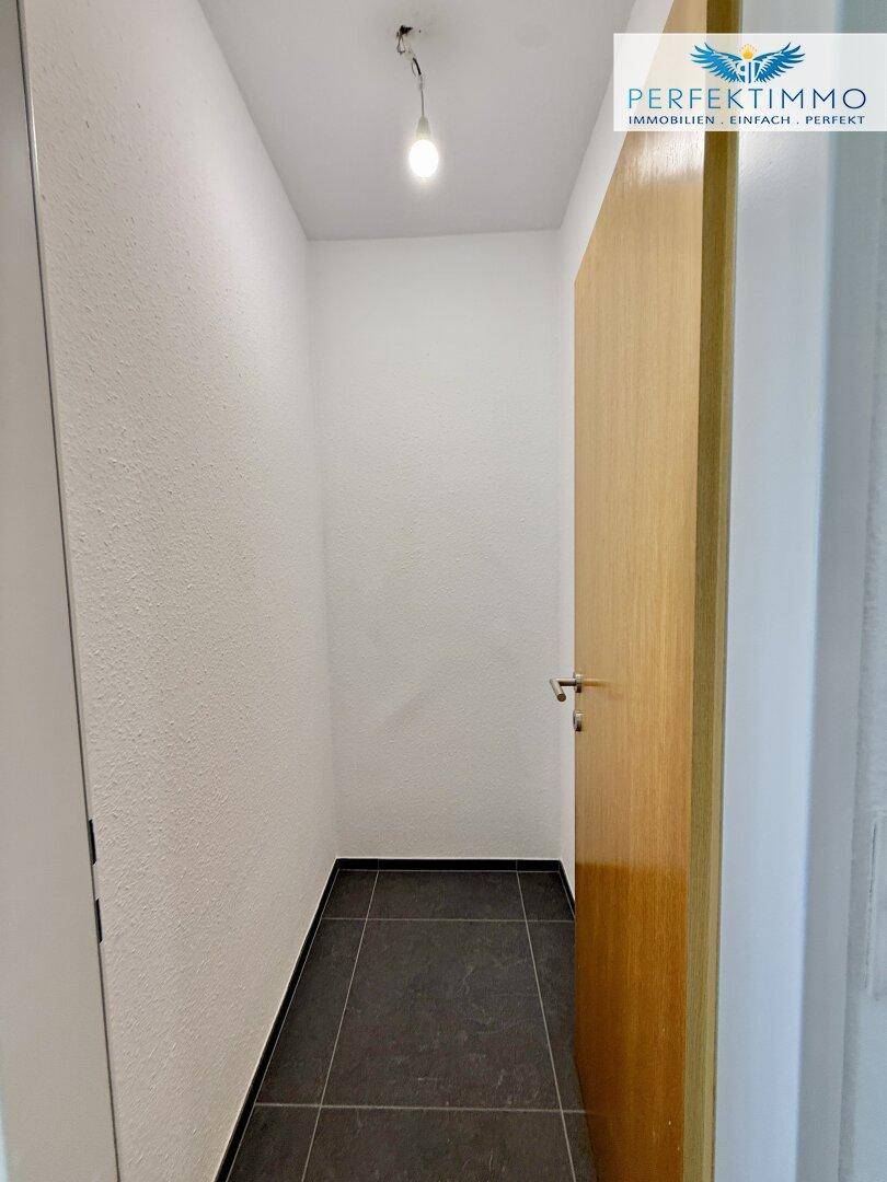 Kleiner Abstellraum mit dunklem Fliesenboden, ideal für zusätzlichen Stauraum.