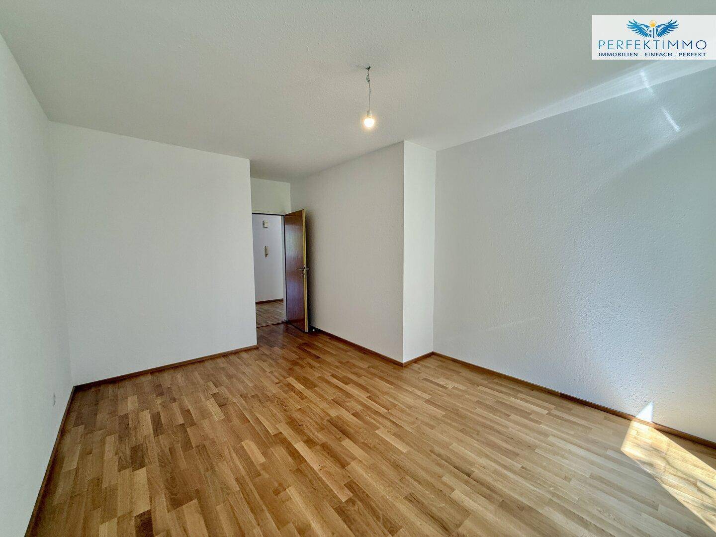 Freundliches Zimmer mit Parkettboden und Zugang zum Flur, vielseitig nutzbar.