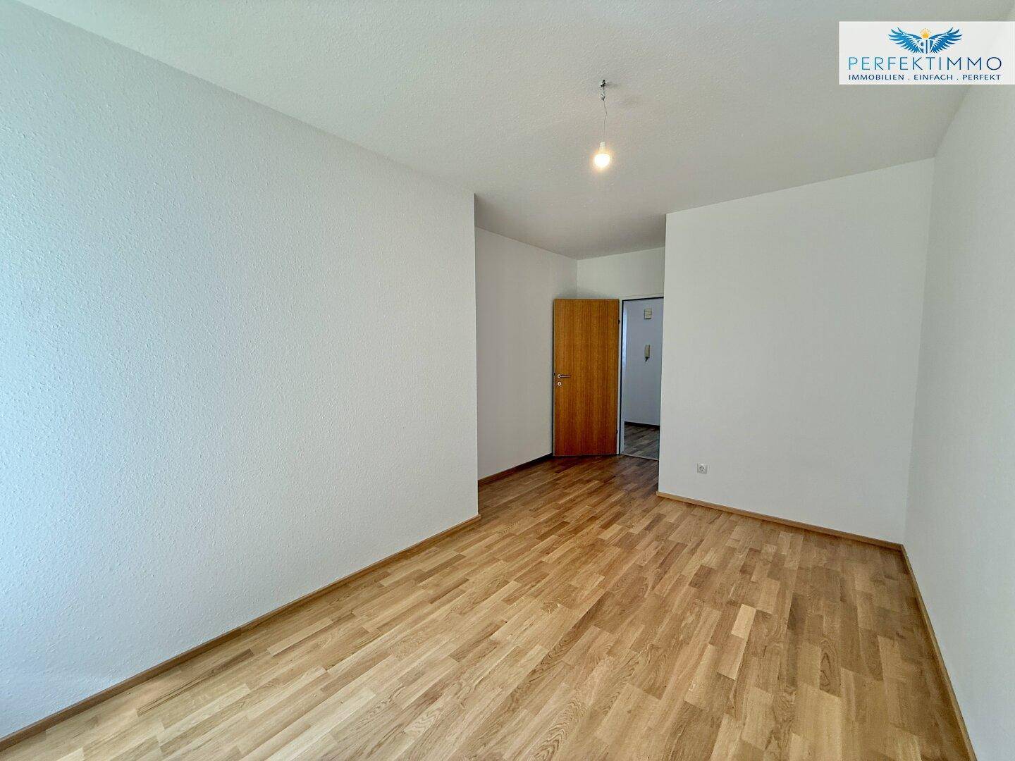 Helles Zimmer mit Parkettboden und Zugang zum Flur, bereit zur individuellen Gestaltung.