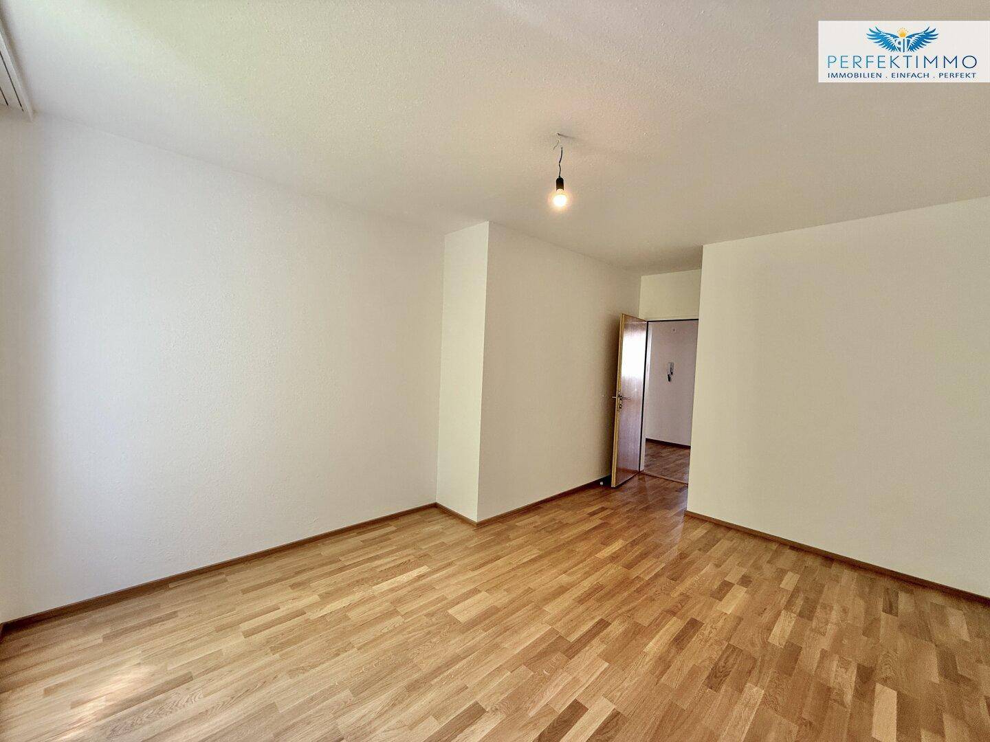 Geräumiges Schlafzimmer mit Parkettboden und Zugang zu weiteren Räumen.